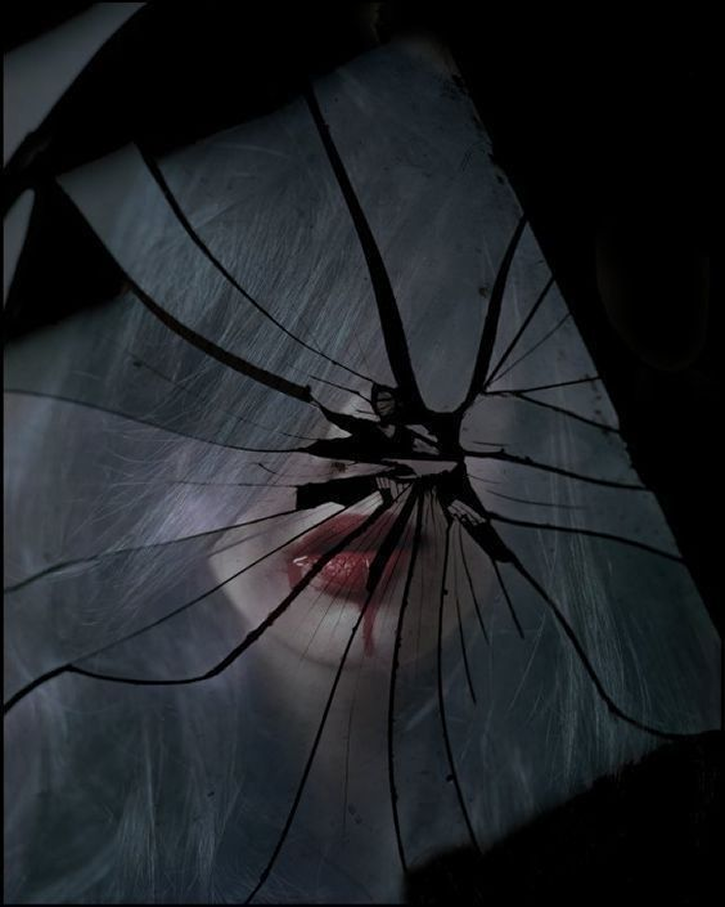 close-up of a shattered antique mirror in a dark room reflecting a dim crimson light and gold dust